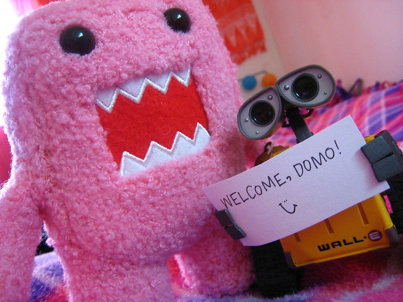 Wall-E toy holds a welcome sign for Domo plush toy