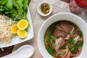 Pho, a Vietnamese rice noodle soup with spiced beef broth and slices of rare steak and condiments such as basil, bean sprouts and lime.