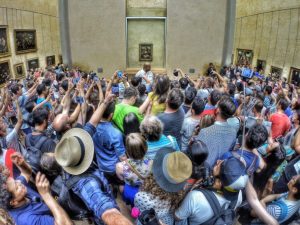 Crowds in Louvre Museum surrounding Mona Lisa painting