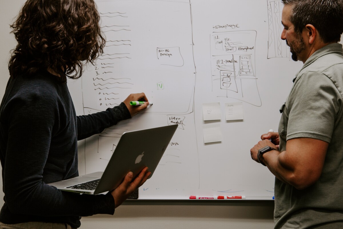 This image displays two individuals brainstorming on a board.