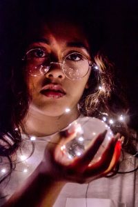 A photo of a girl holding a crystal ball, surrounded by fairy lights.