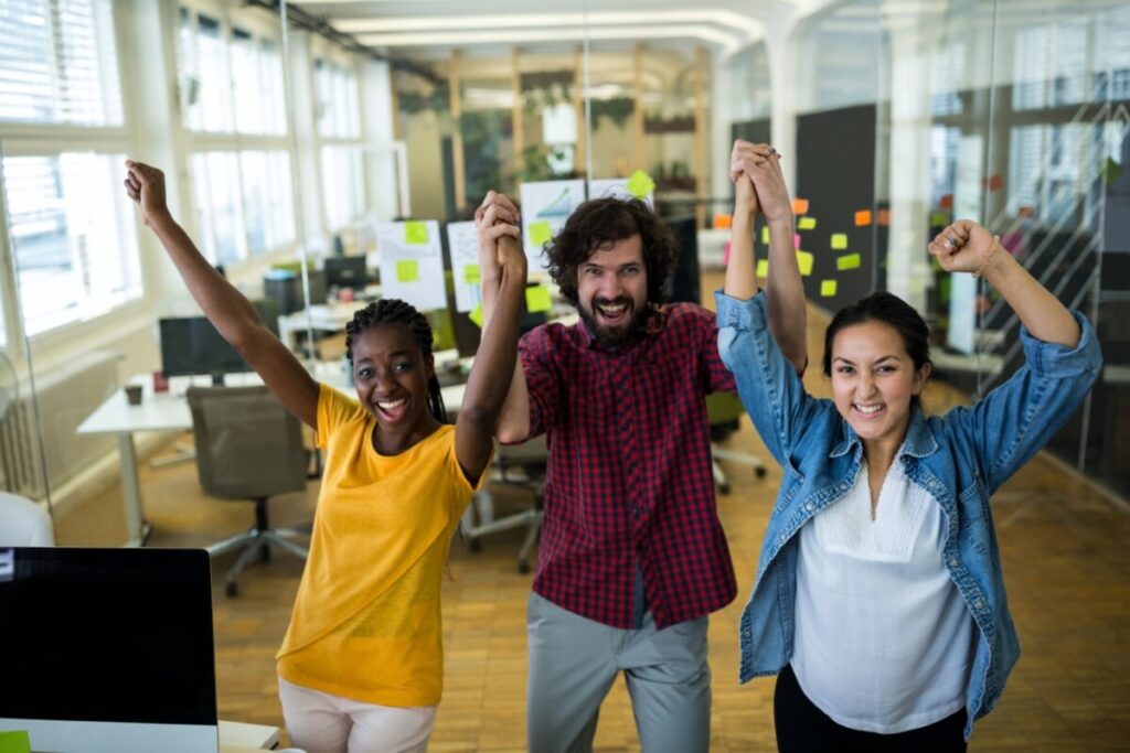 Group of graphic designers cheering together in office