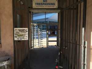 Turnstile with a 'No Trespassing' sign above it, threatening prosecution to violators.