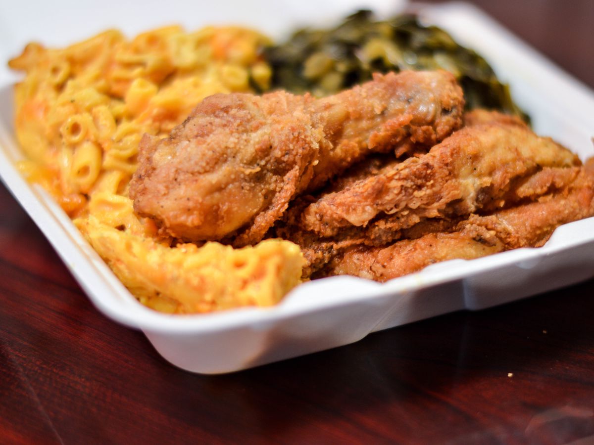 Fried chicken, mac and cheese, and collard greens in a styrofoam container