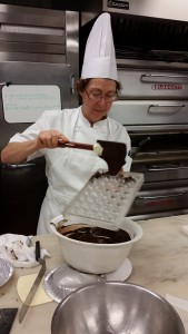 Prof. Hoffman pouring the tempered chocolate into the mold using a spatula.