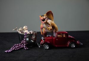 dinosaur, red car, and skeleton in a silver cup