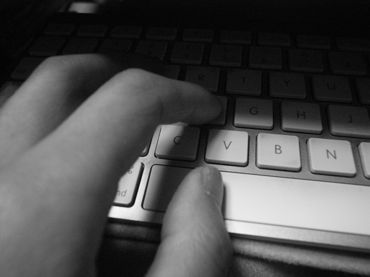 black and white photo of hand typing on keyboard. 