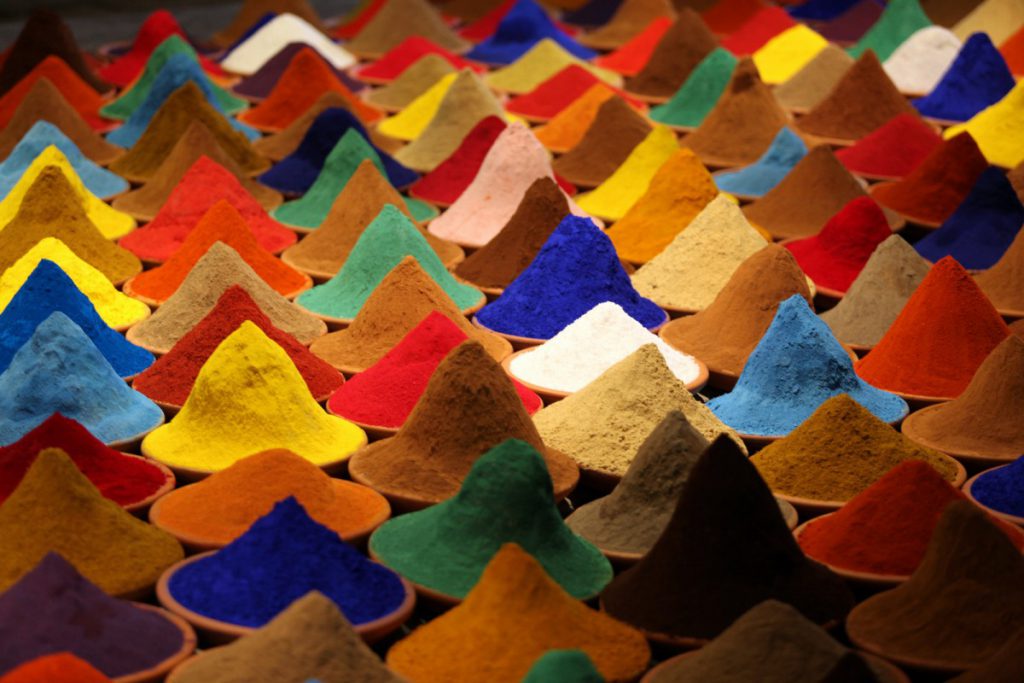 Art installation of small piles of different colored sand on a table.