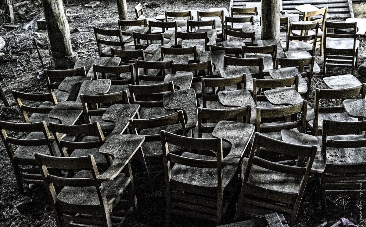Black and white photo of old student desks and chairs crowded together