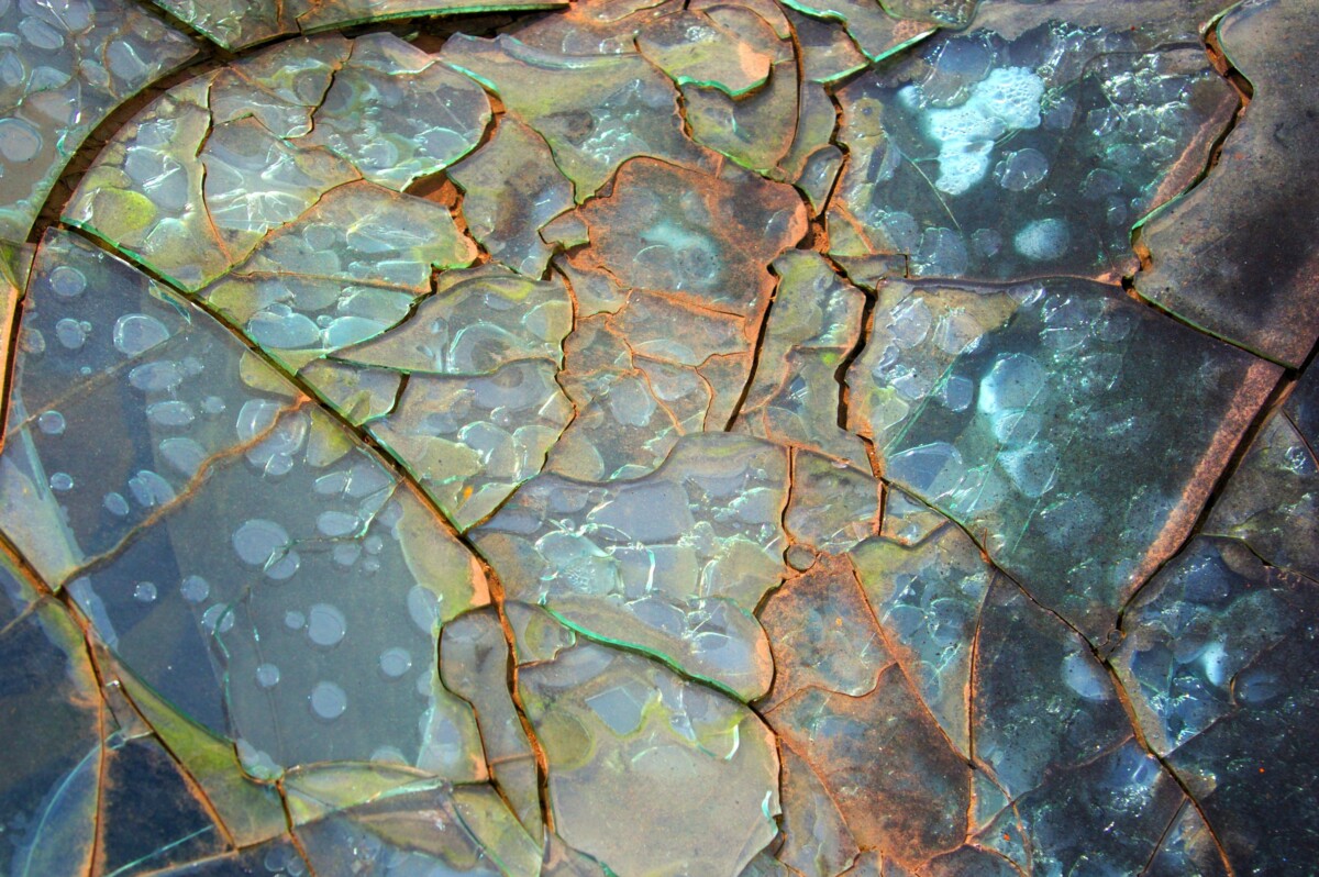 Close-up of cracked, rusted glass with an opalescent sheen