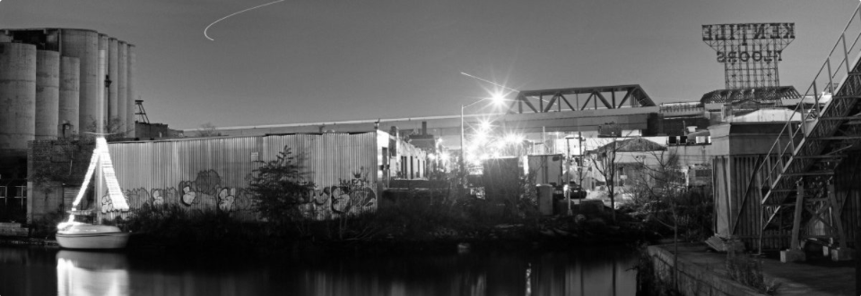 Black and white photo of Gowanus Canal and some surrounding built environment.