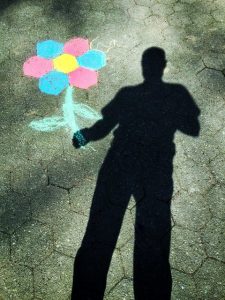 person's shadow holding flower drawn on sidewalk
