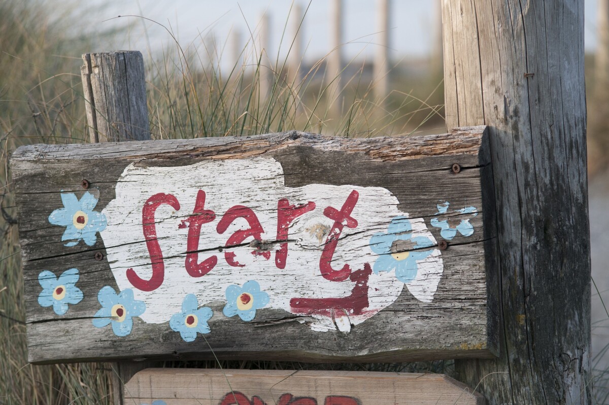 A hand painted start sign on a beach-front fence