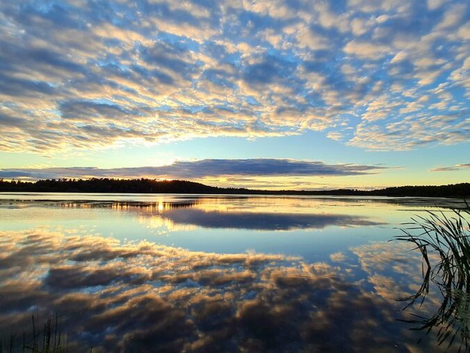 Blue sky with many white clouds reflected in a body of water