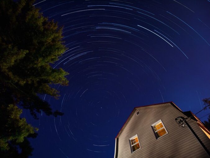 stars streaming through the night sky above a house