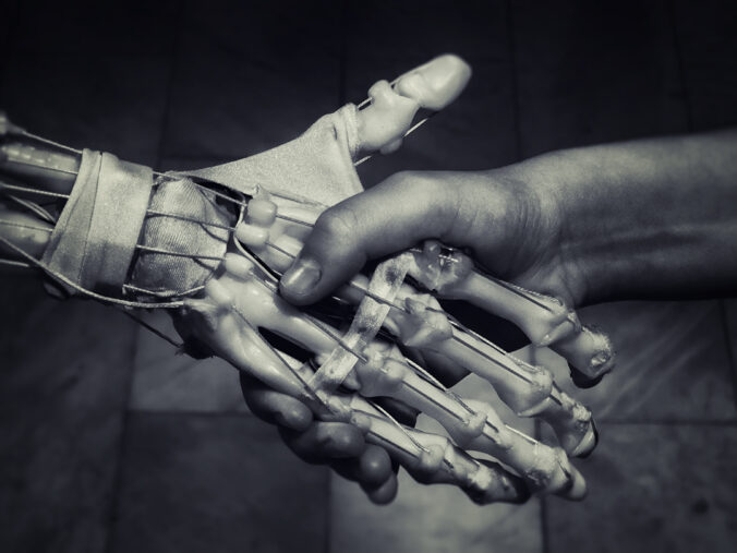 Robot hand and human hand holding hands.