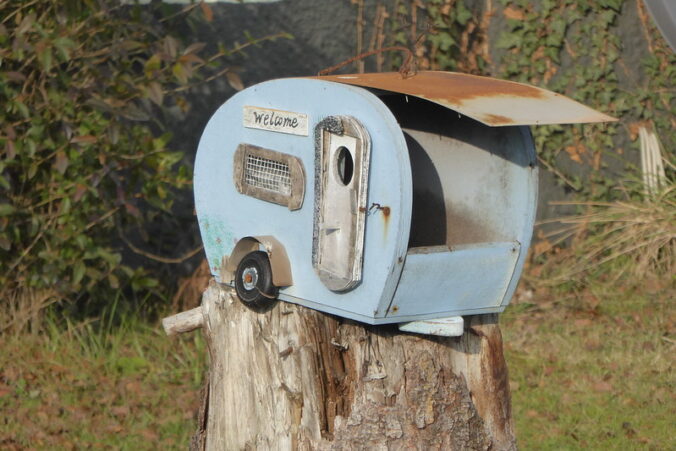Mailbox in the shape of a camper, with the word Welcome on its side