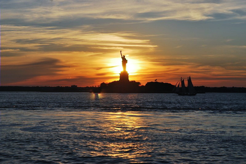 the statue of liberty in front of a blazing sun