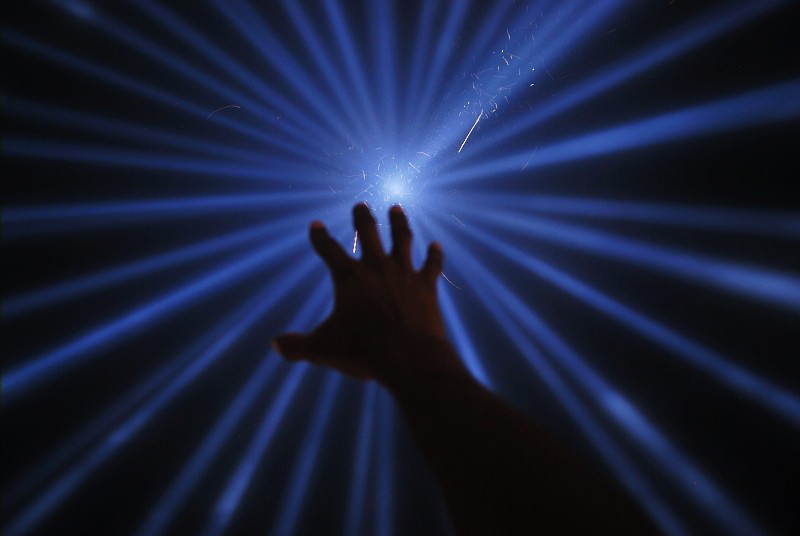 a hand reaching toward rays of blue light