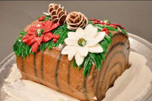 yule log cake covered with frosting flowers and pinecones