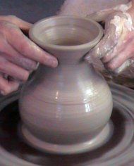 a pair of hands throwing a clay pot
