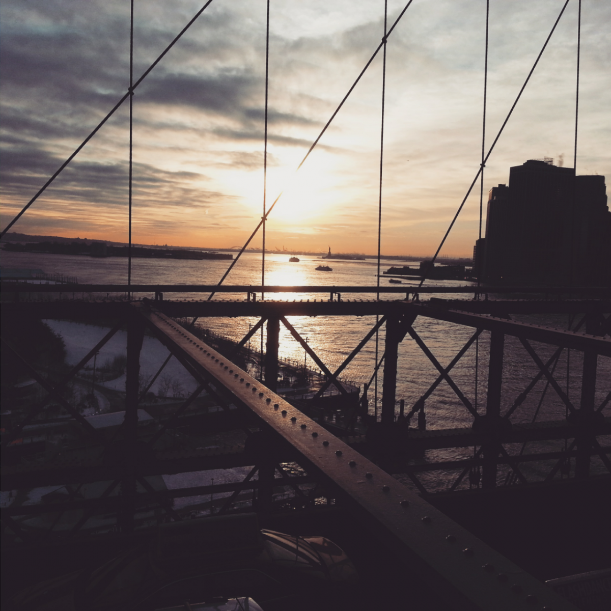 a sunset through a bridge's fence