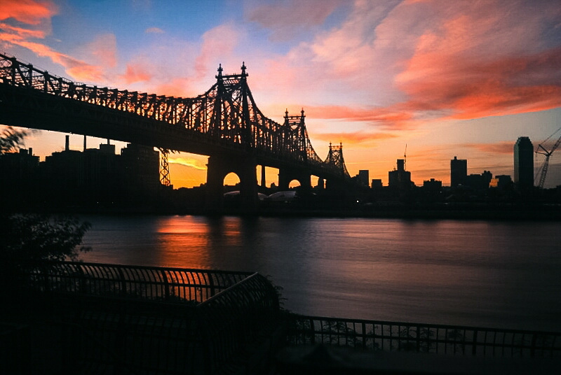 sunrise behind a city bridge