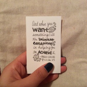 a card that says "and when you want something, all the universe conspires in helping you to achieve it. -Paulo Coehlo"