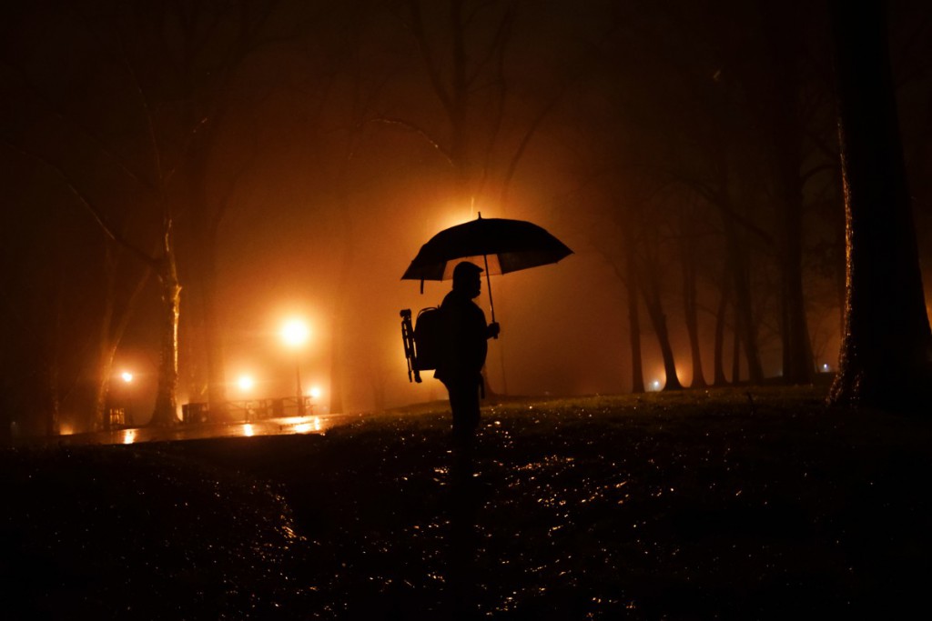 a person holding an umbrella in a park at night