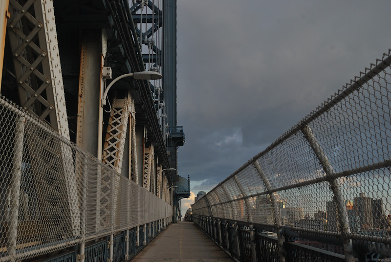 a wire mesh-fence enclosed walkway on a bridge