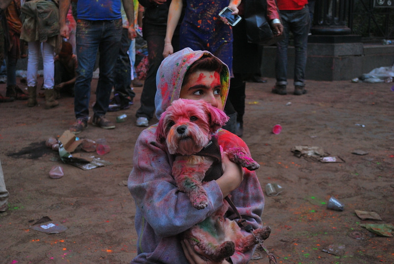 a boy holding a dog, both covered in splashes of paint