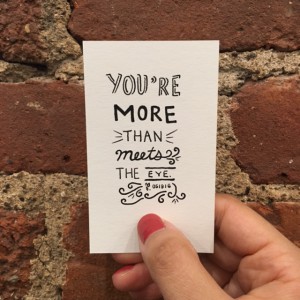 a woman's hand holding a white card that says "You're more than meets the eye."