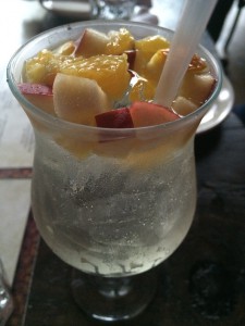fruit floating on top of a clear, carbonated drink in a glass