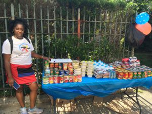 a young woman standing by a table covered in non-perishable food