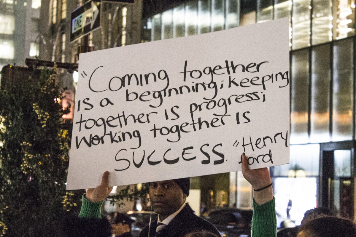 hands holding up a sign that says "Coming together is a beginning; keeping together is progress; working together is success." -Henry Ford