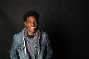 a smiling young man in a jean jacket