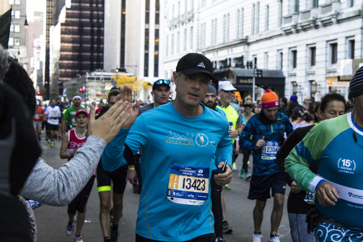 a man in the race wearing a turquoise T-shirt, giving a high five to someone in the crowd