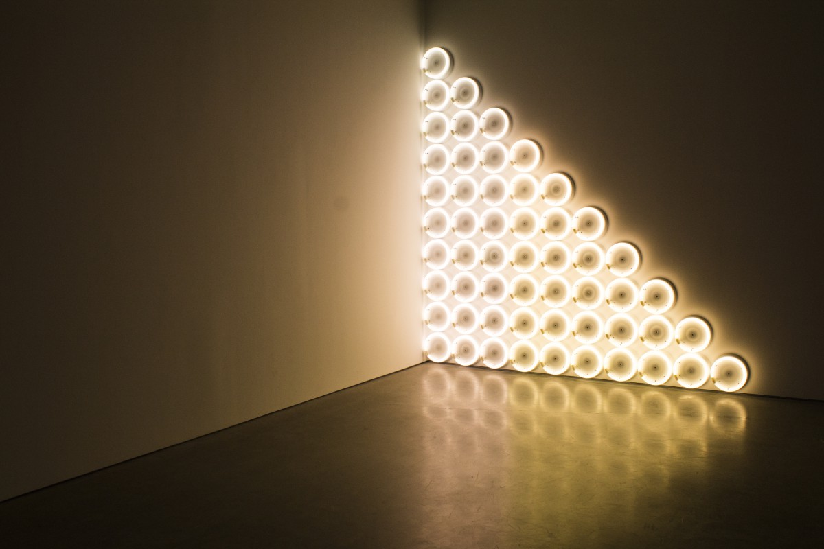 Glowing light sculpture made of circles in an empty room corner