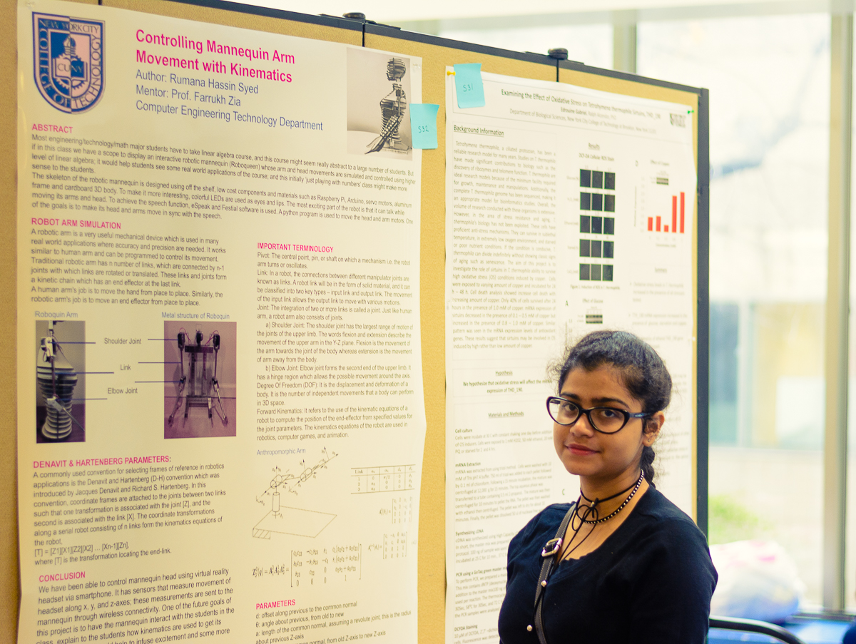 young woman with glasses and braided hair, standing in front of an academic poster