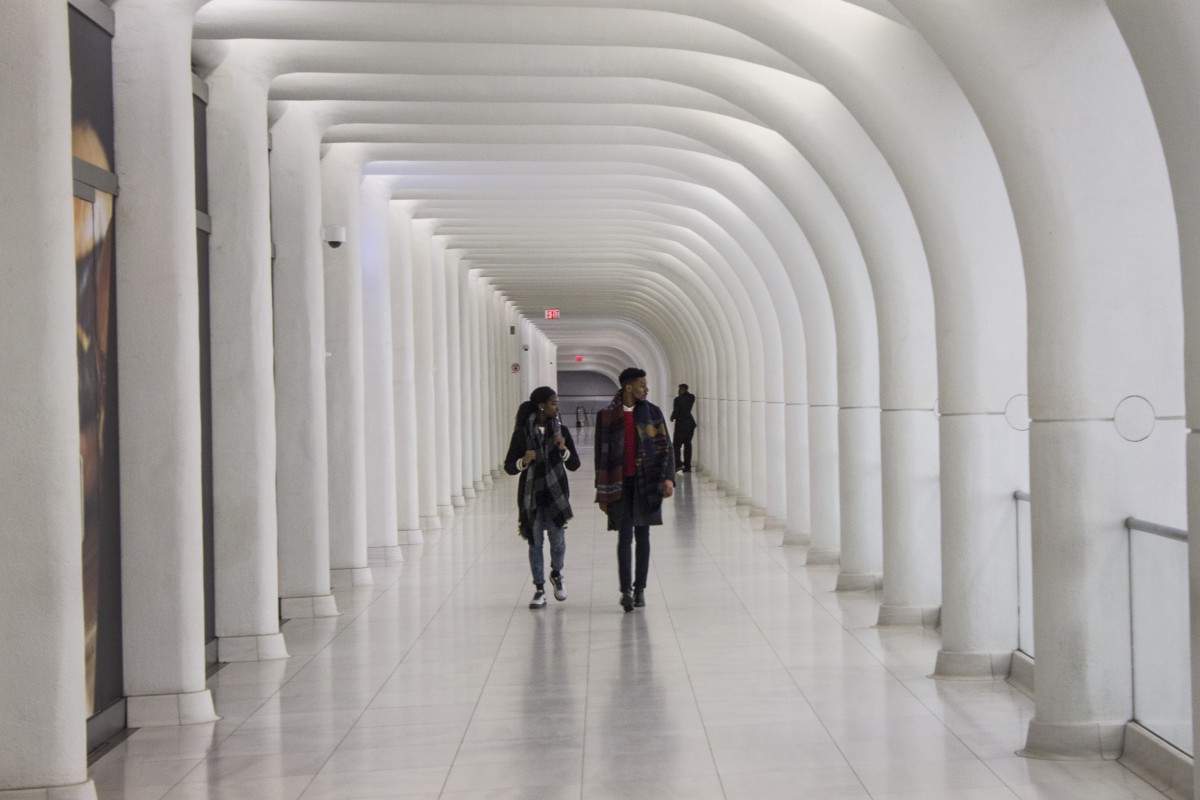 a white hallway with two pedestrians