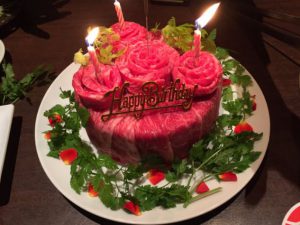 a birthday meat cake with roses made out of red meat