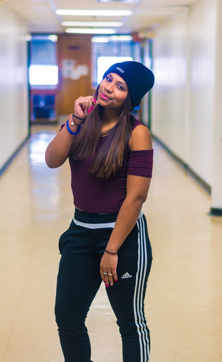 a young woman in a beanie hat and pin-stripe pants
