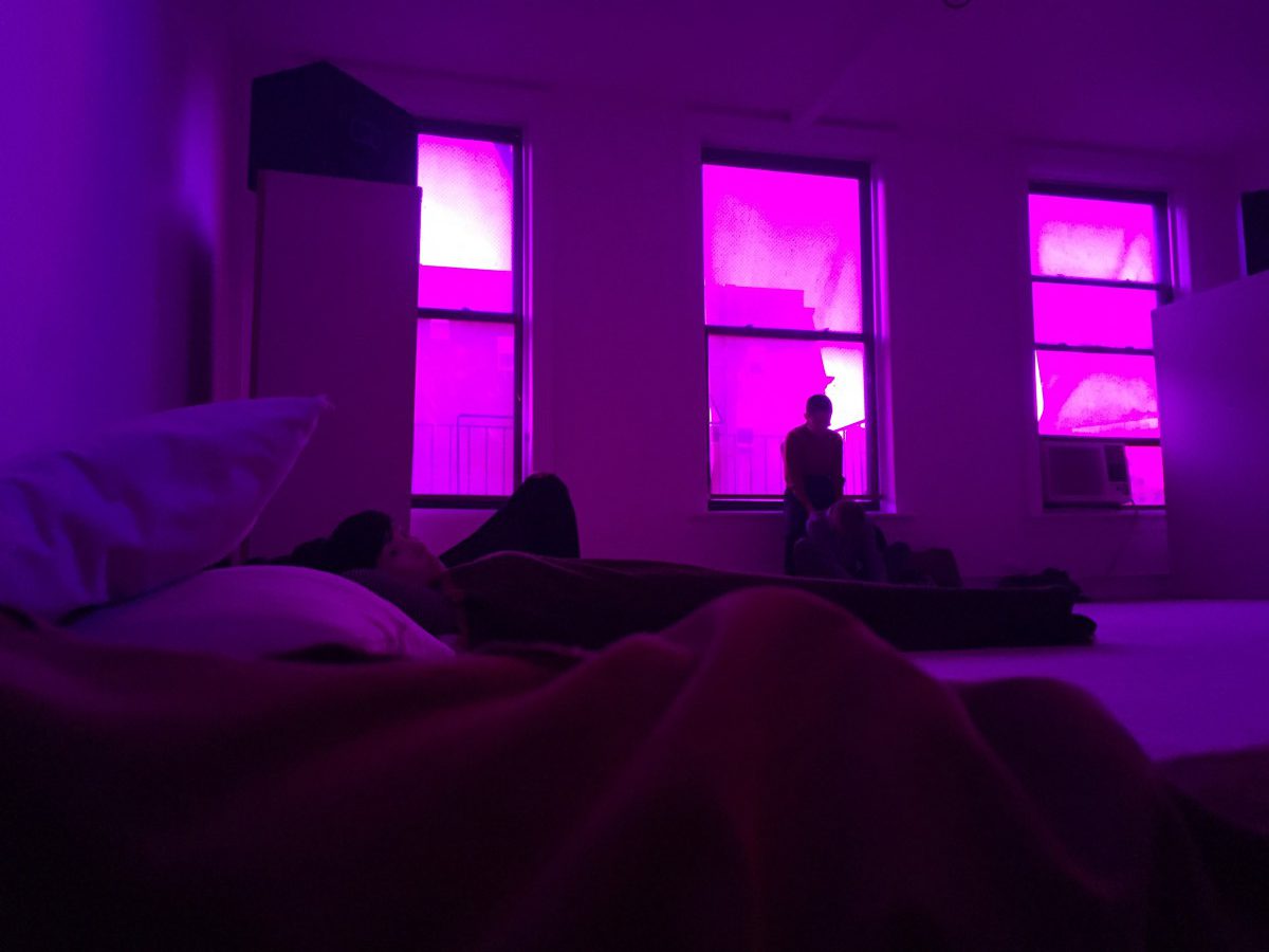 people on mattresses in a purple-lit room