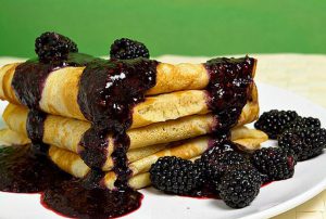 crepes covered in blackberries and syrup