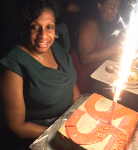 blog author neffi mom smiling over 55 birthday cake with sparkler candle in it
