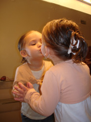 toddler girl kissing her reflection in the mirror