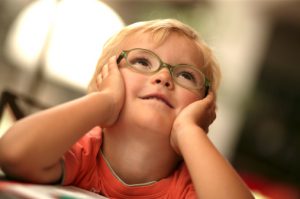 boy with glasses with dreamy eyes looking up