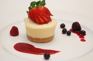 an individual cheesecake on a decorated plate with fruit